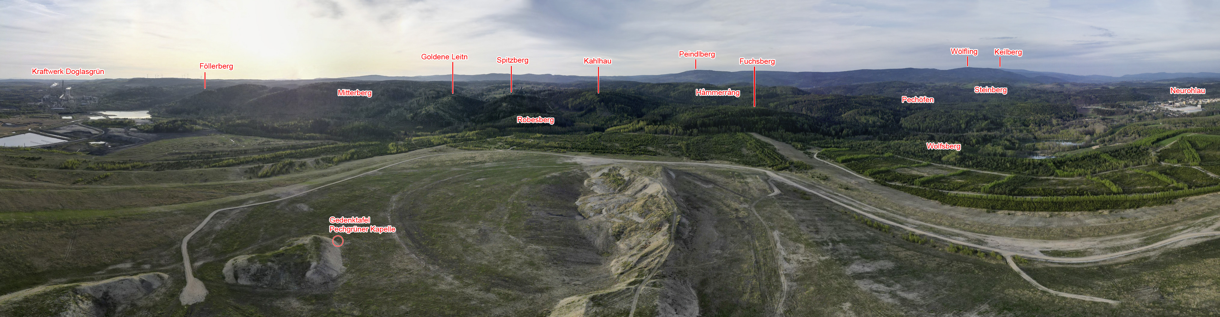 Drohnenpanorama: Blick aus der ehemaligen Dorfmitte nach Norden, beschriftete Höhenzüge am Horizont.